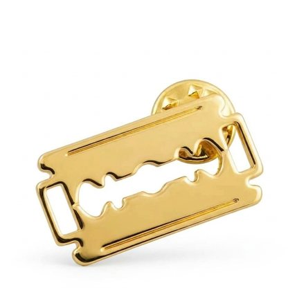 Gold double edge razor blade label pin shown on a white background