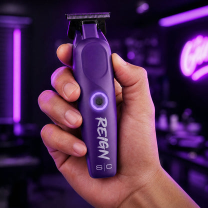 Hand holding a purple grooming tool with 'Reign' branding against a dark background.