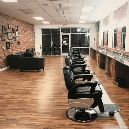 black barber chairs in a line shown in a barbershop or salon positioned in front of a station with mirror